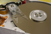 The inside of a hard disk drive displaying the actuator arm traveling over the top platter at extremely high speeds