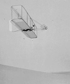 Wilbur Wright pilots the 1902 glider over the Kill Devil Hills, Oct 10, 1902. The single rear rudder is steerable; it replaced the original fixed double rudder.