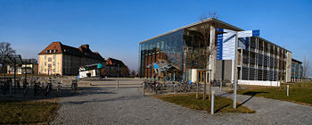 Fakultät für Angewandte Wissenschaften der Universität Freiburg: rechts das Gebäude 101 (Bibliothek, Hörsäle, Seminarräume, Dekanat), in der Mitte zwei Lehrstuhlgebäude, links hinten die Mensa; die Objekte in der Mitte sind Teile der Installation Jump and Twist by Dennis Oppenheim.