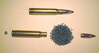 A present-day rifle cartridge (this example is a .30-06) and its component parts: primer, brass case, powder, and bullet.