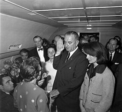 Former U.S. President Lyndon Baines Johnson takes the oath of his office with his left hand on a Bible.