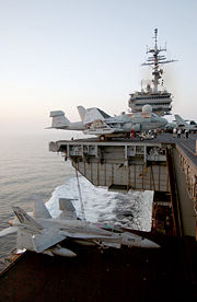 An F/A-18C fighter jet on an aircraft elevator of the USS Kitty Hawk