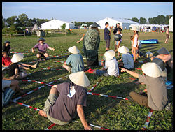Go played using humans wearing hats (black or white) in place of stones (black or white) on a grid laid out in the grass.