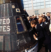 President Kennedy looks at the spacecraft Friendship 7, which made three earth orbits piloted by astronaut John Glenn at Kennedy's right, February 23, 1962, Cape Canaveral, Florida