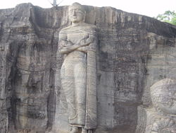 Ananda Thera (center) standing by Lord Buddha (partly visible at right, reclining) at Gal Vihare