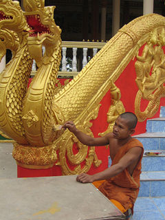 Monk repainting a naga (mythical dragon) at Pha That Luang