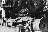 Poles erected barricades, such as this one on Napoleon Square, throughout Warsaw, making it difficult for German infantry and tanks to operate. In background: Captured Hetzer tank destroyer.