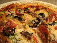 A homemade pizza exhibiting a plethora of toppings common to American pizzas