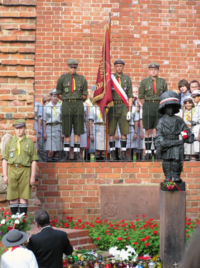 Statue of Mały Powstaniec (The Little Insurgent), just outside Warsaw's medieval city walls, commemorates the child soldiers that fought in the Warsaw Uprising. The boy wears a captured German helmet with Polish national colors. Honor guard of Polish Boy Scouts.