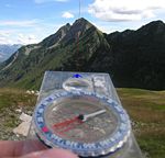 When the needle is aligned with and superimposed over the outlined orienting arrow on the bottom of the capsule, the degree figure on the compass ring at the direction-of-travel (DOT) indicator gives the magnetic bearing to the target (mountain).
