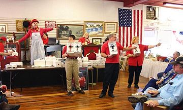 An auctioneer and her assistants scan the crowd for bidders