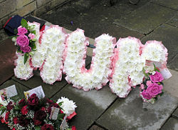 A floral name tribute (spelling out the word "MUM") at a funeral in England.
