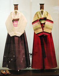 Hanbok from a shop window showing two styles. Notice the traditional shoes on the lower left side.