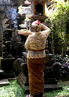 Balinese Hindu woman placing daily offerings on her family shrine