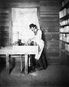 A potter molds pottery with his hands while operating the mechanical potter's wheel with his foot, 1902.