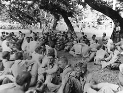 Group of American prisoners, note Japanese guard with fixed bayonet, on the "March of Death" from Bataan to the prison camp at Cabanatuan. May 1942.