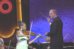 David Eaton of the New York City Symphony conducts a young violinist and orchestra