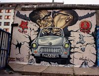 A preserved section of the Berlin Wall at the East Side Gallery featuring Leonid Brezhnev and Erich Honecker riding together in an East German Trabant. Image made in the Spring, 2002 by Peter Rimar.