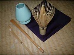 A set of implements for the Japanese tea ceremony. From bottom left: chashaku (tea scoop), sensu (fan), whisk shaper, chasen (bamboo whisk) and fukusa (purple silk cloth)