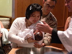 Mother holds her child to be baptized