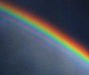 A contrast-enhanced photograph of a supernumerary rainbow, with additional green and purple arcs inside the primary bow.