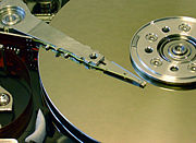 The inside of a hard disk drive with the cover removed. To the left is the actuator arm, with the read-write head at its end suspended over the platters.