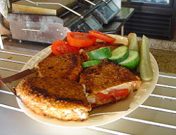 A typical Bagel Toast served with tomatoes, pickles, and cucumber. The sandwich press toasters are in the background.