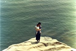 Mother holding infant near ocean