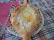 Adjaran khachapuri, filled with cheese and topped with a raw egg.