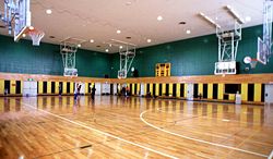 Modern indoor gymnasium with pull-down basketball hoops.