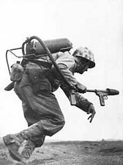 A Marine flamethrower operator runs under fire on Iwo Jima