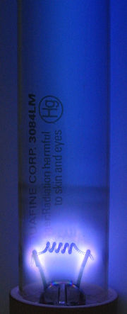 The unfiltered ultraviolet glow of a germicidal lamp is produced by a low pressure mercury vapor discharge (identical to that in a fluorescent lamp) in an uncoated fused quartz envelope