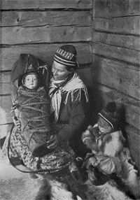 Warm Hearts of the North by Borg Mesch (1917). The Lapland father may measure his wealth in herds of reindeer, in hides and pelts, but the Lapland mother knows that her bright-eyed, smiling baby and her sturdy two-year-old are treasures beyond price.