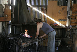 A blacksmith works at his forge.