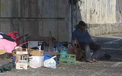 Homeless person with a collection of possessions, living under a bridge in Rome
