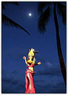 Hula ʻauana. A woman performs hula under moonlight, part of a hula themed show prepared for visitors to the islands.