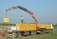A loader crane offloading aerated concrete bricks at a building site