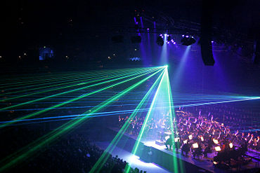 Low-intensity lighting and haze in a concert hall allows laser effects to be visible.