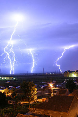 Lightning is an example of plasma present at Earth's surface. Typically, lightning discharges 30,000 amperes, at up to 100 million volts, and emits light, radio waves, X-rays and gamma rays. Plasma temperatures in lightning can approach 28,000 kelvin and electron densities may exceed 1024/m3.