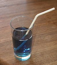 A straw dipped in a colored solution appears to be broken, because of the refraction of light as it passes from the solution to the air.