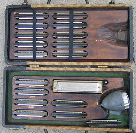 A musician's case full of harmonicas in a variety of keys, complete with a bullet microphone.