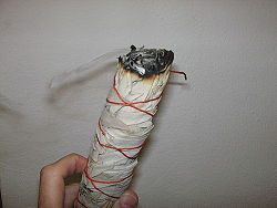 A home-made smudge stick, with herbs wrapped up in paper.