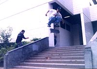 A skater performs a kickflip over an 11-set of stairs.