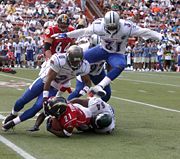 A running back being tackled when he tries to run with the ball