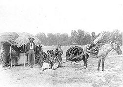 Stump Horn and family (Northern Cheyenne); showing home and horsedrawn travois.