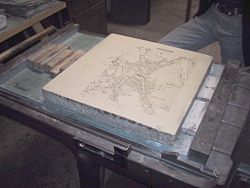 A limestone plate with a negative map of Moosburg, Bavaria, is prepared for a lithography print.
