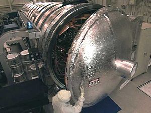 An engineer opens a large vacuum chamber