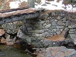 Dry set masonry supports a rustic log bridge, where it provides a well-drained support for the log (this will increase its service life).